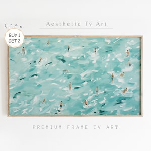 Op de afbeelding: Een ingelijst schilderij van een turquoise oceaan met witte golven en veel kleine figuren die in het water zwemmen. Het schilderij heeft een licht houten lijst en de tekst "PREMIUM FRAME TV ART" is onder de lijst gedrukt.