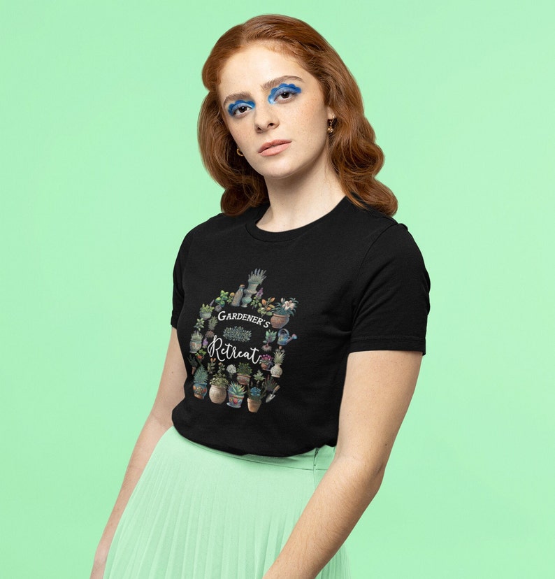 May include: A black t-shirt with a graphic design of a circle of potted plants and gardening tools. The text "GARDENER'S RETREAT" is in the center of the design.
