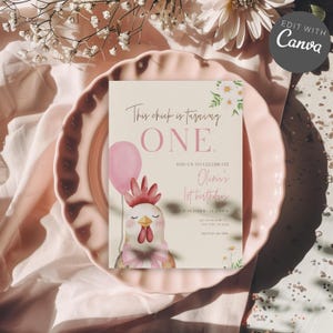 Op de afbeelding: Blush roze uitnodigingskaart met de tekst "This chick is turning ONE" en "Olivia's 1st birthday". De kaart toont een aquarel illustratie van een kuiken met een roze ballon. De uitnodiging ligt op een roze bord.