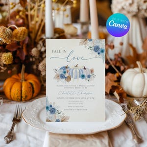Op de afbeelding: Een uitnodiging voor een bruidsdouche met de woorden "Fall in Love" in elegant schrift. De uitnodiging toont aquarel pompoenen in blauwe en witte tinten, omringd door bloemaccenten. De tekst bevat de naam van de bruid, datum, tijd en locatie.