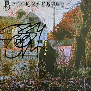 Puede incluir: Portada del álbum debut homónimo de Black Sabbath. La imagen presenta una casa de estilo gótico, una mujer con un vestido negro y el nombre de la banda en la parte superior. La portada del álbum está firmada por Ozzy Osbourne.