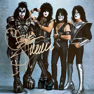 Puede incluir: Una fotografía en blanco y negro de la banda de rock KISS. Los miembros de la banda llevan su maquillaje y vestuario característicos. La imagen está firmada por la banda.