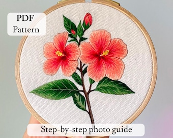 May include: Embroidered floral pattern in a wooden hoop. The design features two vibrant coral hibiscus flowers with yellow centers, green leaves, and a bud. Text on the image reads "PDF Pattern" and "Step-by-step photo guide".