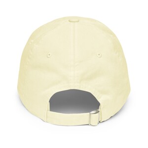 May include: A plain, light yellow baseball cap with an adjustable strap in the back.