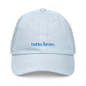 Könnte beinhalten: Eine hellblaue Baseballkappe mit dem Schriftzug "tutto bene." in Blau gestickt.