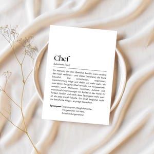 May include: A black and white printable definition card for the word "Chef". The definition describes a chef as someone who stays calm under pressure, is a leader, and inspires others. The card also includes synonyms for the word "Chef".