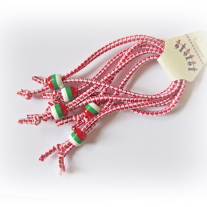 May include: A pack of red and white elastic hair ties with green, white, and red beads. The beads are in the shape of a flag.
