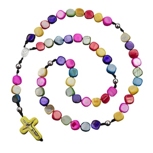 May include: A colourful multi-strand rosary necklace with square-shaped beads. The beads are made of iridescent mother of pearl and are strung on a black cord. The rosary features a silver crucifix with a yellow background and a depiction of Jesus.