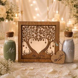 Peut inclure: Un ensemble de cérémonie de sable de mariage en bois. L'ensemble comprend un cadre en bois avec un motif d'arbre, deux bouteilles de sable et un cœur en bois. Le cadre porte les noms "Alissa & Parker" et la date 08.08.2028 gravés.