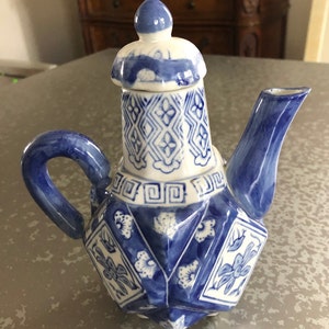 May include: A blue and white porcelain teapot with a lid. The teapot has a geometric design with floral accents.