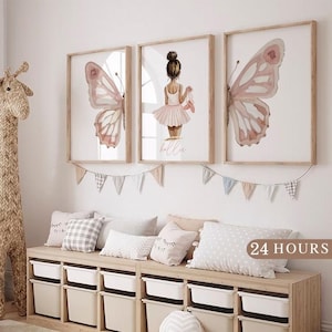 May include: Three framed watercolor prints with butterfly and ballerina themes. The butterfly prints feature pink and white wings. The ballerina print shows a girl in a pink tutu holding ballet shoes. The prints are above a storage bench with pillows.