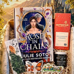 May include: A gift box containing the book Rose in Chains by Julie Soto, a Moonstruck milk chocolate bar with cinnamon, a black candle labeled Meet Me at the Bookstore, a bookmark with a green-clad figure, and two butterfly and garden stickers.