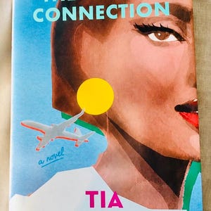 May include: A book cover titled The Missed Connection by Tia Williams. The illustration features a close-up of a person's face with dark hair, winged eyeliner, and red lips. A small grey airplane, a yellow circle, and the text a novel are visible.