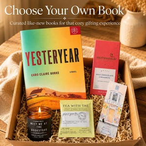 May include: A gift box containing a Yesteryear novel by Caro Claire Burke, a Moonstruck milk chocolate cinnamon bar, a Tea With Tae jasmine green tea sachet, a bookstore bookmark, and a Meet Me At The Bookstore scented candle in a glass jar.
