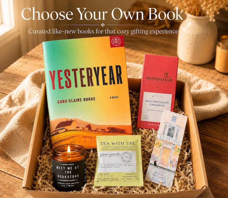 May include: A gift box containing a Yesteryear novel by Caro Claire Burke, a Moonstruck milk chocolate cinnamon bar, a Tea With Tae jasmine green tea sachet, a bookstore bookmark, and a Meet Me At The Bookstore scented candle in a glass jar.