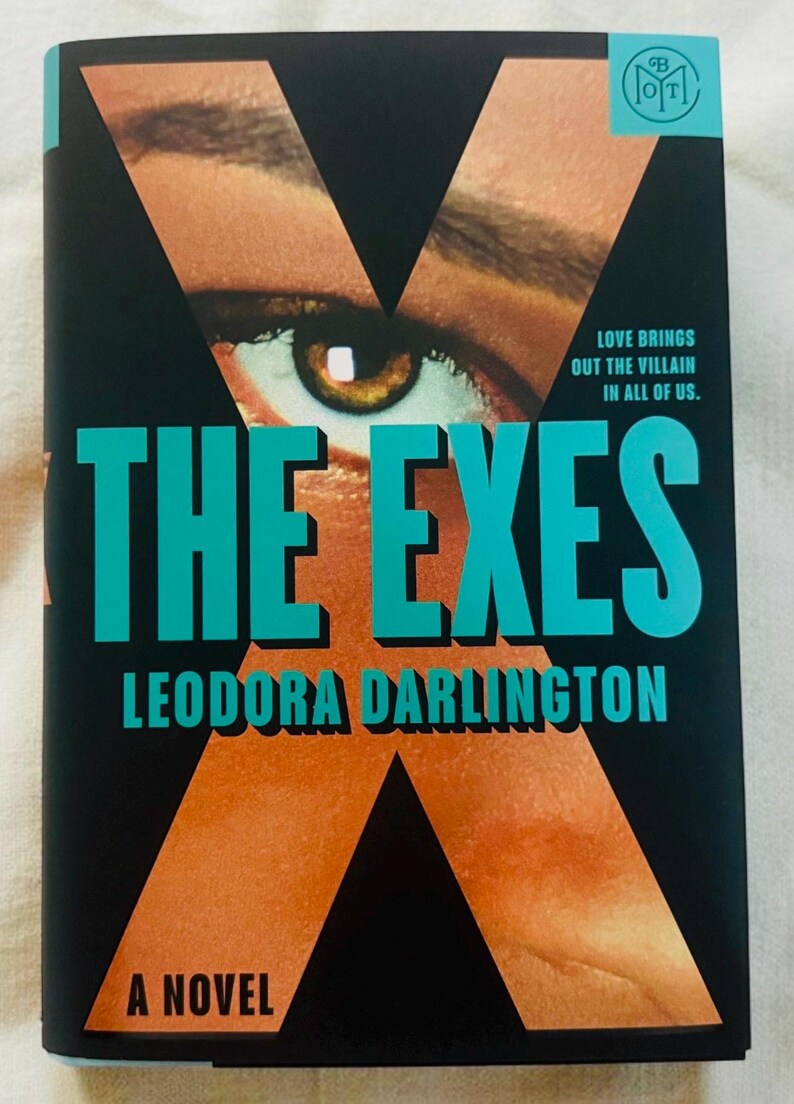 May include: A book titled The Exes by Leodora Darlington with a black cover featuring a large orange letter X, a close-up of a human eye, and the text Love brings out the villain in all of us. The title is in large teal letters on the front.