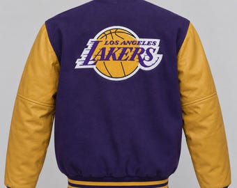 May include: A purple varsity jacket with gold leather sleeves and a large Los Angeles Lakers basketball team logo embroidered on the back. The jacket features a ribbed collar, cuffs, and hem with purple and gold stripes, and a button-up front.