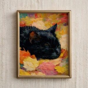 Puede incluir: Impresión artística enmarcada de un gato negro sobre hojas de otoño coloridas. La pintura, en un marco dorado, presenta un estilo impresionista con hojas en tonos amarillos, naranjas y rosas.