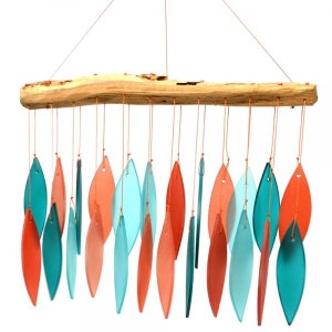 May include: A driftwood wind chime with teal and coral colored glass leaves. The leaves are suspended from the driftwood by strings.