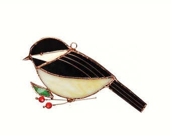 Könnte beinhalten: Ein Ornament aus Buntglas, das eine Kohlmeise zeigt, die auf einem Zweig mit roten Beeren sitzt. Der Vogel hat einen schwarzen Kopf und Rücken, weiße Wangen und eine gelbe Brust. Das Ornament ist aus Glas und Kupfer gefertigt.