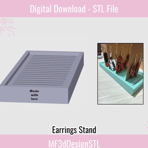 May include: A light blue earring stand with slots for displaying earrings. The stand is made of plastic and has the words "Made with love" printed on the front.