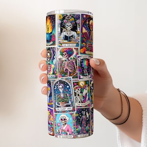 Hand holding a 20oz tumbler wrapped in a colourful, sarcastic tarot card sublimation design featuring vivid skeleton motifs.