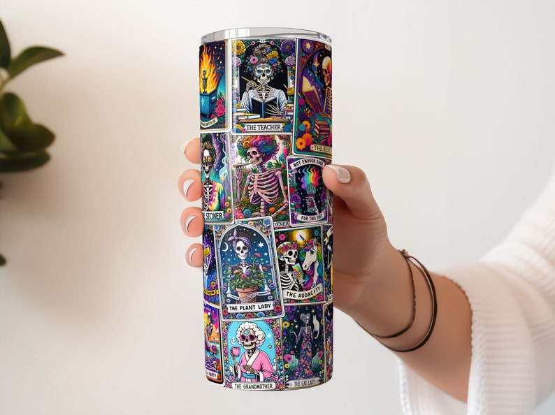 Hand holding a 20oz tumbler wrapped in a colourful, sarcastic tarot card sublimation design featuring vivid skeleton motifs.