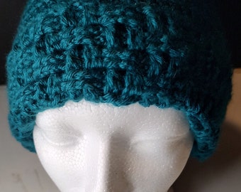 May include: Teal blue crocheted beanie hat on a white mannequin head.