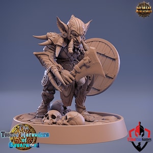 May include: A detailed miniature figurine of a goblin warrior, painted in a light brown colour. The goblin is holding a large axe in one hand and a shield in the other. The goblin is wearing armour and has a fierce expression on its face. The miniature is standing on a base with skulls.