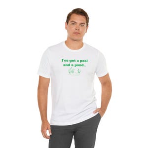 May include: White t-shirt with green text that reads "I've got a pool and a pond..." with a small green illustration of a pond with reeds.