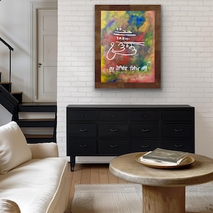 Könnte beinhalten: Ein gerahmtes Wandkunstwerk mit einem lebendigen, mehrfarbigen abstrakten Hintergrund mit gemischten Gelb-, Blau-, Grün- und Rottönen. Das Kunstwerk zeigt weiße kalligrafische Gurmukhi-Schriftzeichen und Symbole in der Mitte.