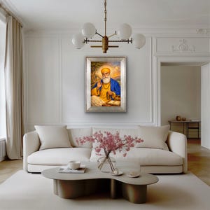 May include: A framed portrait of a religious figure in a yellow turban and blue robes. The artwork is displayed on a white wall above a white sofa and a modern coffee table. A chandelier hangs above the artwork.