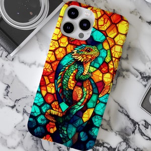 May include: A colorful phone case with a stained glass design featuring a green lizard with a yellow crest. The case has a mosaic pattern with shades of blue, yellow, orange, and red.