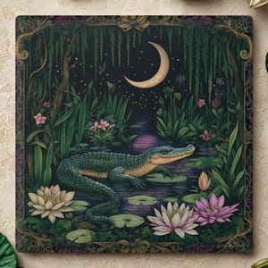 May include: Square artwork featuring an alligator in a swamp scene with a crescent moon. The artwork has a dark green and blue color palette, with pink and white water lilies. The alligator is green with a yellow underbelly.