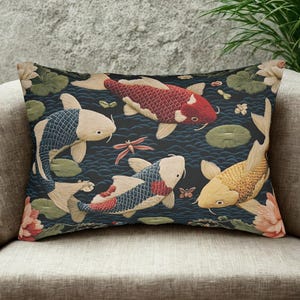 May include: Rectangular decorative pillow featuring a Japanese koi pond design. The pillow displays colorful koi fish in shades of red, gold, and blue, swimming among lily pads and flowers against a dark blue background. The pillow is placed on a beige sofa.
