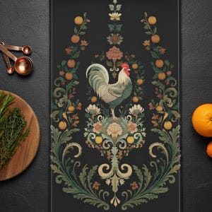 Puede incluir: Una toalla de cocina negra con una ilustración detallada de un gallo sobre un diseño floral. El gallo tiene plumas verdes y blancas y una cresta roja. El diseño incluye frutas naranjas y follaje verde.