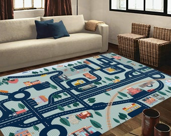 Puede incluir: Una alfombra de juego azul y gris con un diseño de calle de ciudad. La alfombra presenta carreteras, edificios, árboles y vehículos. Es perfecta para que los niños jueguen con coches y camiones de juguete.