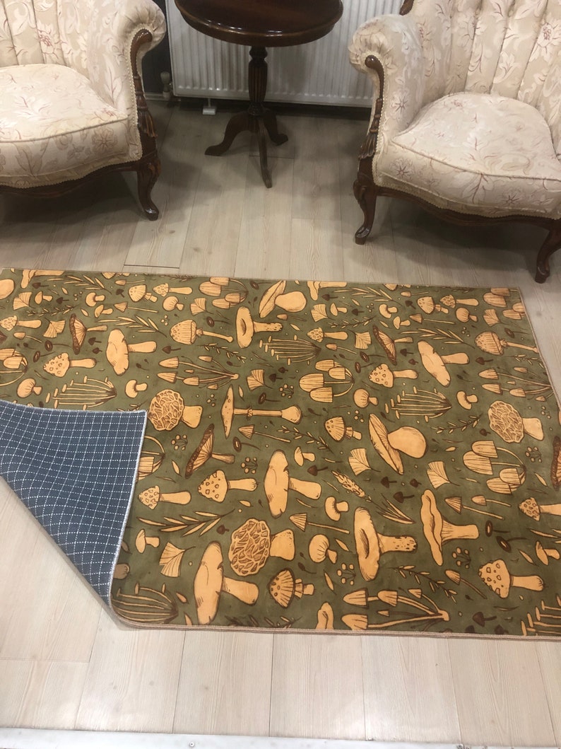 May include: A green and brown area rug with a mushroom pattern. The rug has a brown border and a non-slip backing.