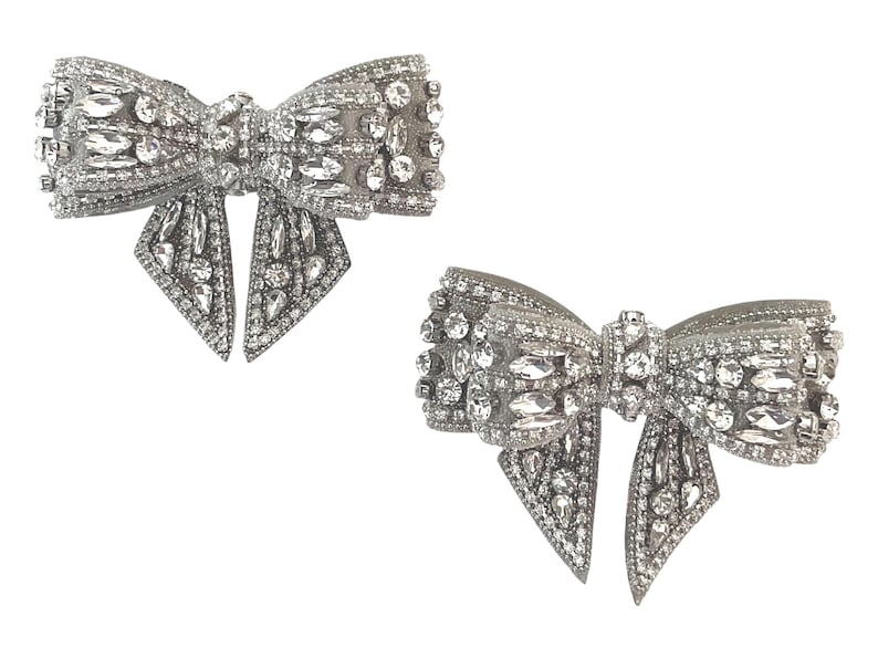 May include: Two silver bow-shaped brooches with crystal embellishments.