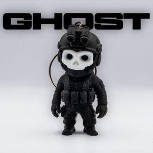 May include: Black keychain featuring a miniature figurine of a soldier with a skull-shaped mask. The figurine is wearing tactical gear and a helmet with night vision goggles. The word "GHOST" is displayed in bold, black letters above the figurine.
