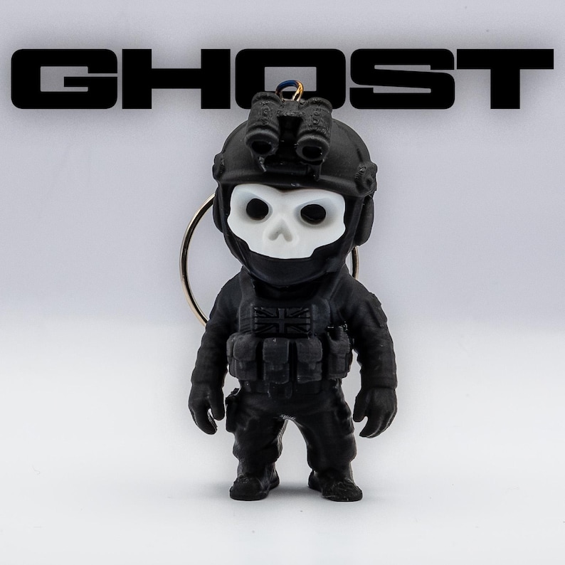 May include: Black keychain featuring a miniature figurine of a soldier with a skull-shaped mask. The figurine is wearing tactical gear and a helmet with night vision goggles. The word "GHOST" is displayed in bold, black letters above the figurine.