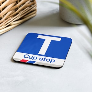May include: A blue and white coaster with the letter "T" and the text "Cup stop".
