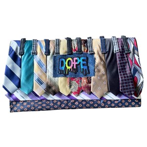 May include: A rectangular clutch bag constructed from various neckties in diverse colors and patterns, including stripes, paisley, and geometric prints. A central blue denim patch features the word DOPE in colorful, dripping-style lettering.