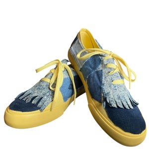 May include: A white ceramic mug with a black handle and the text "But First, Coffee" in a bold, black font. The mug is set against a blurred background, suggesting a cozy setting.