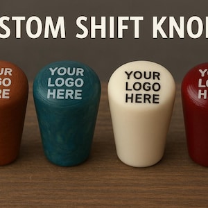 May include: Four custom shift knobs in a row, each with "YOUR LOGO HERE" in white text. The knobs are in shades of brown, teal, cream, and red. The text "CUSTOM SHIFT KNOBS" is at the top.