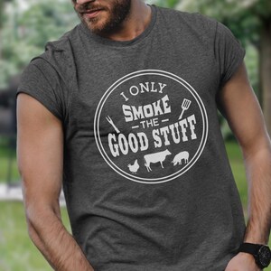 May include: A gray t-shirt with a white circle graphic that says "I only smoke the good stuff" with a grill spatula, a fork, a chicken, a cow, and a pig inside the circle.