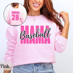 May include: Light pink sweatshirt with the word "MAMA" in a bold, pink font and "Baseball" in a cursive black font. The back of the sweatshirt has the name "Jackson" and the number "28" in pink. The sweatshirt is a light pink color.