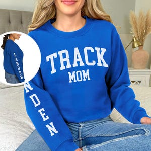 May include: A royal blue sweatshirt with the text "TRACK MOM" in white on the front and the name "LANDEN" in white on the sleeve.