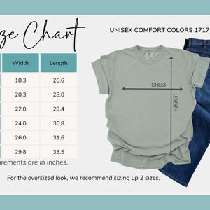 May include: Sage green unisex t-shirt with a size chart showing chest and length measurements in inches. The chart includes sizes S to 4XL, with width ranging from 18.3 to 29.8 inches and length from 26.6 to 33.5 inches. Blue jeans are also in the image.
