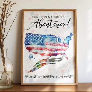 Könnte beinhalten: Gerahmter Druck mit einer Aquarellkarte der USA, die die Farben der amerikanischen Flagge verwendet. Der Druck enthält deutschen Text: "FÜR DEIN NÄCHSTES Abenteuer!" und "Reisen ist eine Investition in sich selbst."